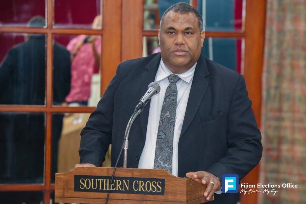 An Electoral Commission of Fiji official speaking at a lectern
